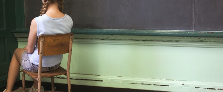 Girl sitting in corner facing wall