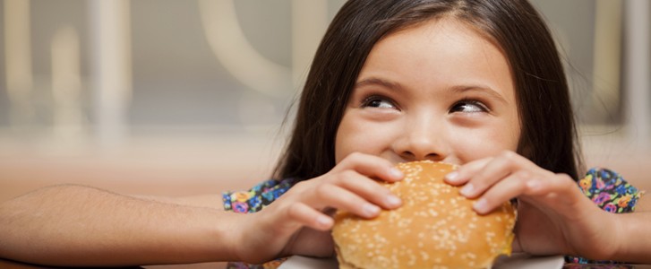Little girl eating a hamburger at a family dinner