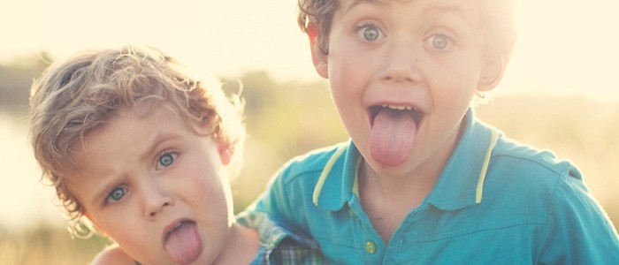 Two male toddlers sticking out their tongues
