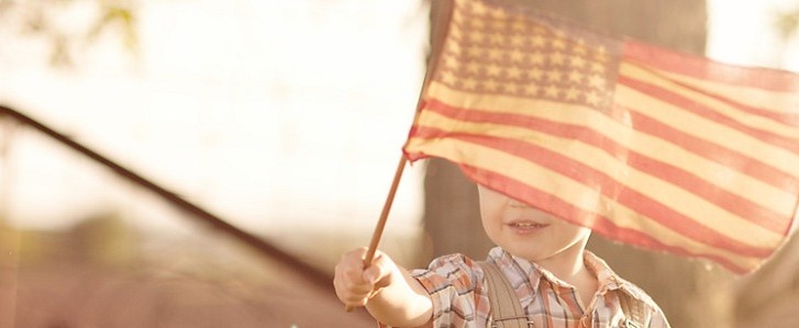 Young boy waving American flag at sunset