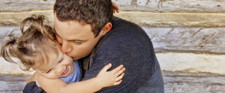 dad hugs and kisses young daughter
