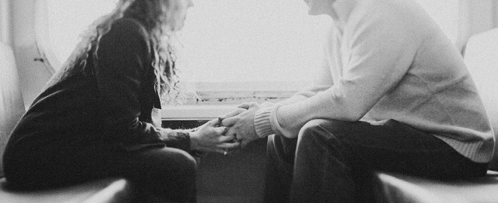 Couple sitting face-to-face holding hands