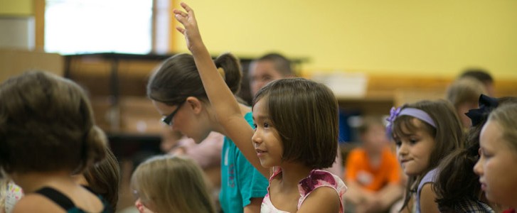 Little girl raising her hand during class