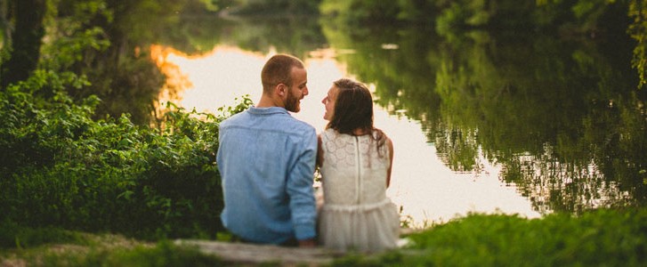 Happy engaged couple relaxing by a river bed